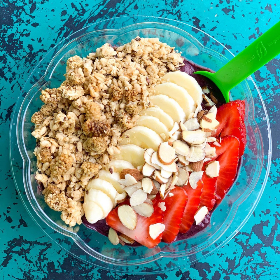 A Juice Parlor NoHo acai bowl with granola, banana, sliced strawberries, and almonds.